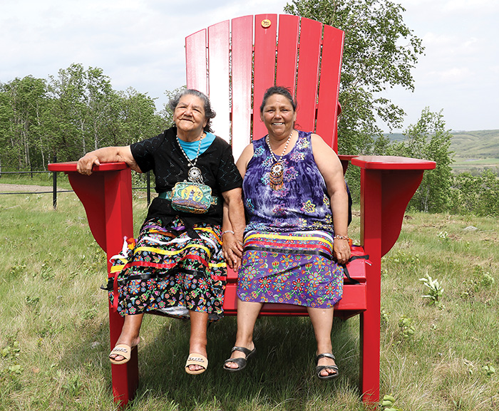 Marjorie Boyer and Anne Stubodden enjoying the Giant Adirondack Chair at the Fort Ellice site, located near St. Lazare, Manitoba. <br />